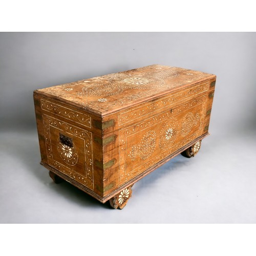 122 - A very large Syrian Teak dowry chest.Inlaid bone designs. Raised on wheels.Late 19th / early 20th ce... 