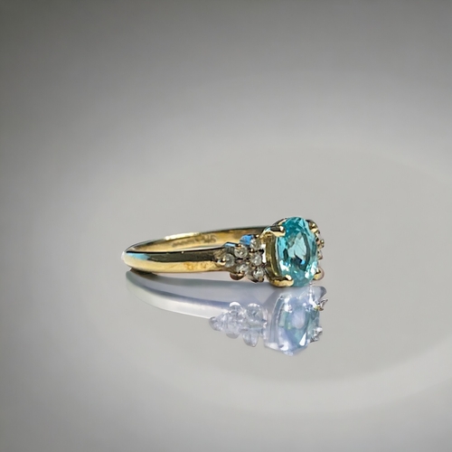 526 - A ladies 9ct Gold ring. Set with central blue stone, possibly Topaz? bordered with six diamonds. Siz... 