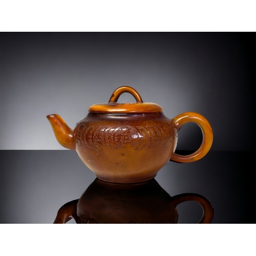 49 - A CHINESE CARVED AMBER TEAPOT.
Qing dynasty. 
Carved Tokens with script to body and lid. 
Impressed ... 