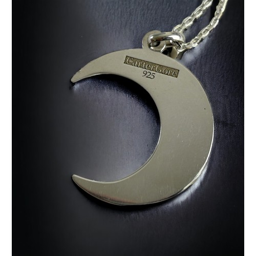 223 - A silver Cart Gore Crescent moon shaped pendant. On a silver chain.