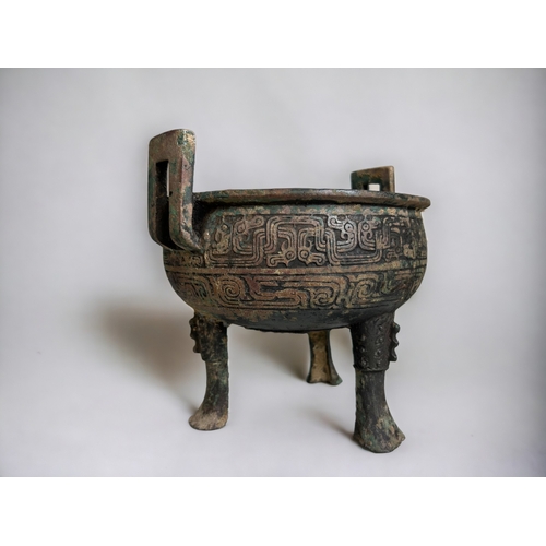 109 - A Chinese bronze ritual ding.Round body raised on tripod legs and twin handled. scrolling Leiwen des... 