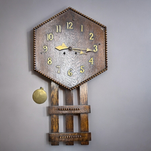 792 - An Oak Arts & Crafts wall clock.Hexagonal dial with brass Arabic numbers.80 x 41cm