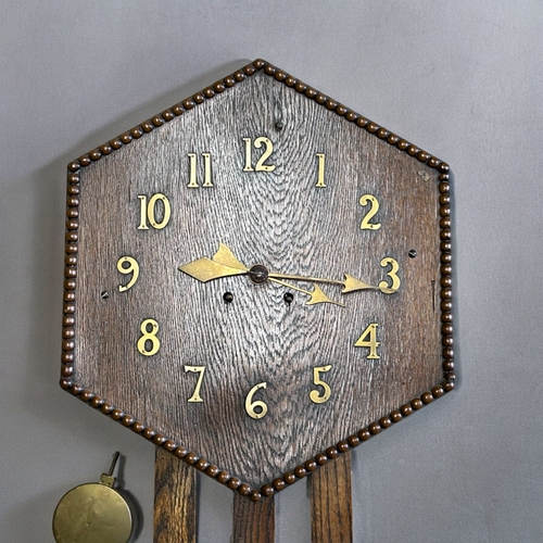 792 - An Oak Arts & Crafts wall clock.Hexagonal dial with brass Arabic numbers.80 x 41cm