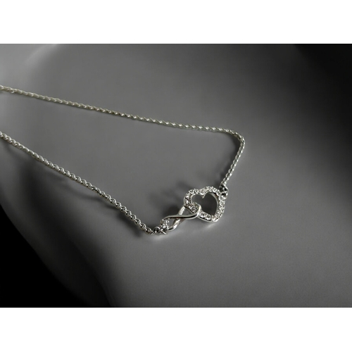 518 - A silver heart infinity bracelet. Together with a silver, enamel & marcasite 'flower' brooch.