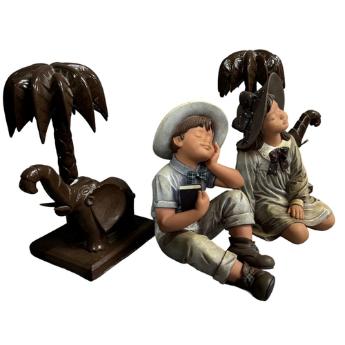 225 - Two Large Nadal Figurines of seated children and a pair of carved wooden palm trees with Elephants.