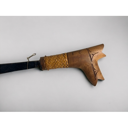 632 - An ornamental Iban parang with a 20-inch blade and carved wooden handle. The carved wooden sheath wi... 