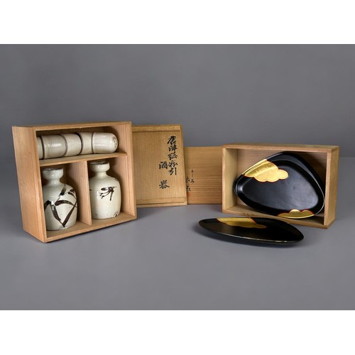 146 - A boxed Japanese pottery Sake set.Together with a boxed set of lacquer serving dishes.