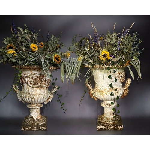 164 - A large pair of Victorian cast iron garden Urn planters.With twin mask handles, raised on square pli... 