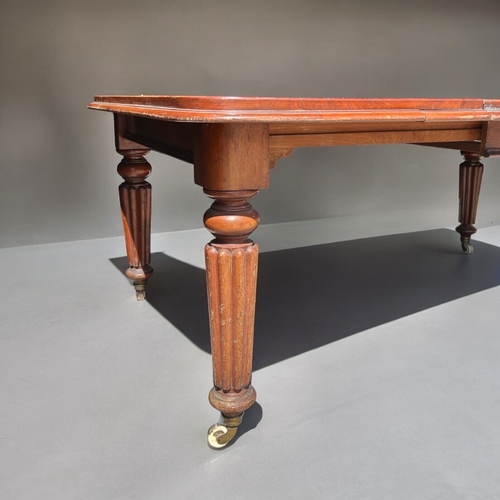 157 - A 19th century Mahogany wind-out extending table.Turned & fluted legs, raised on casters. Two dr... 