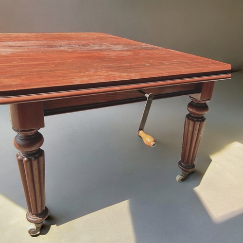 157 - A 19th century Mahogany wind-out extending table.Turned & fluted legs, raised on casters. Two dr... 