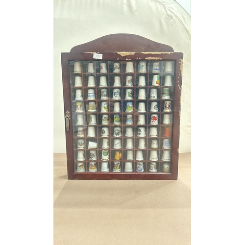 66 - Wooden display case contains assorted collectible ceramic thimbles with a variety of designs and mot... 