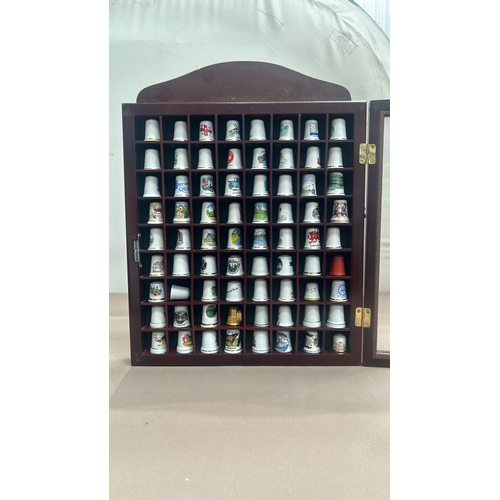 66 - Wooden display case contains assorted collectible ceramic thimbles with a variety of designs and mot... 