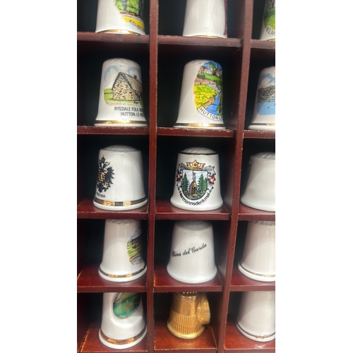 66 - Wooden display case contains assorted collectible ceramic thimbles with a variety of designs and mot... 