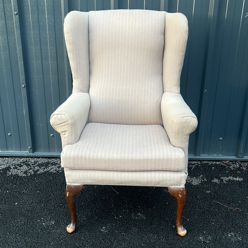 91 - Upholstered beige wingback armchair with curved wooden legs. Vintage style.