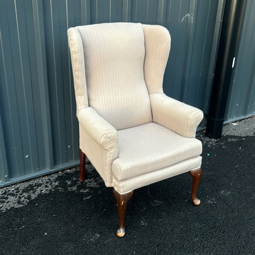 91 - Upholstered beige wingback armchair with curved wooden legs. Vintage style.