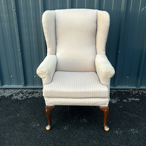 91 - Upholstered beige wingback armchair with curved wooden legs. Vintage style.