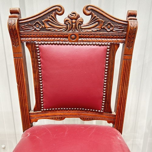 272 - Victorian-style mahogany chairs, set of two, feature red leather upholstery and decorative carving. ... 