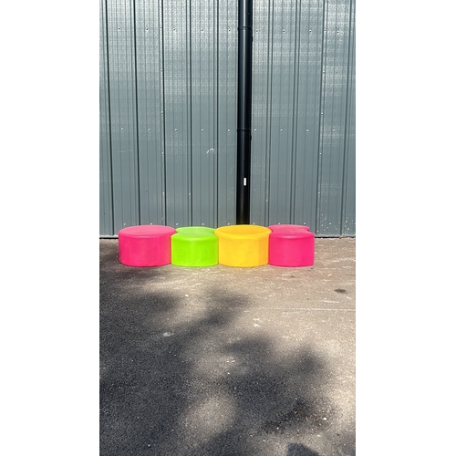 280 - Set of four vibrant cylindrical ottomans in pink, green, and yellow, upholstered in durable fabric.