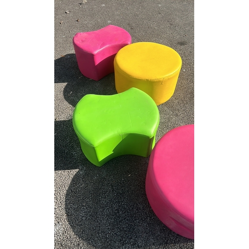 280 - Set of four vibrant cylindrical ottomans in pink, green, and yellow, upholstered in durable fabric.