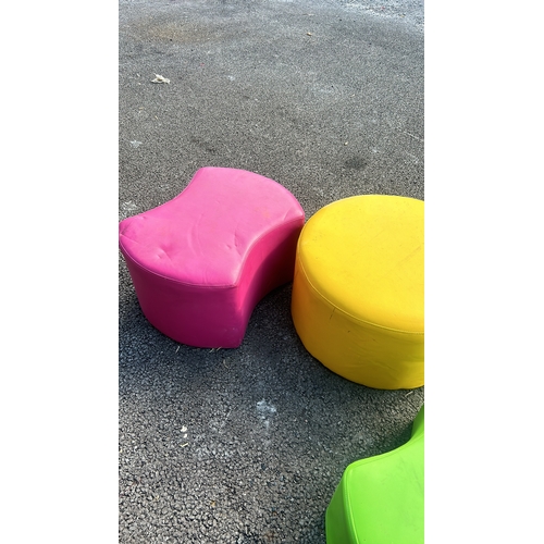 280 - Set of four vibrant cylindrical ottomans in pink, green, and yellow, upholstered in durable fabric.