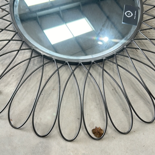 298 - Round wall mirror with a sunburst design, featuring black metal loops and a central mirrored surface... 