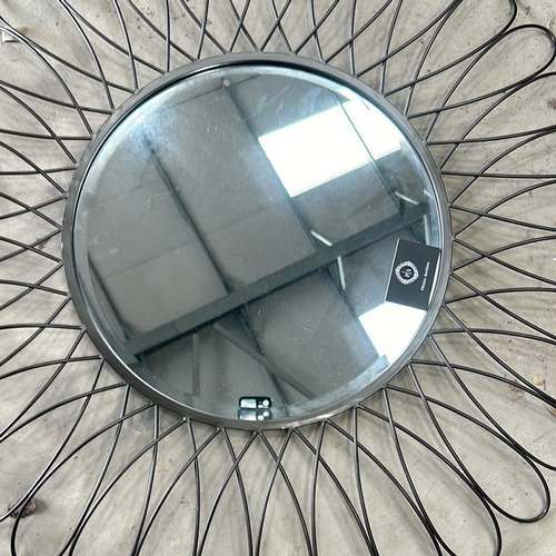 298 - Round wall mirror with a sunburst design, featuring black metal loops and a central mirrored surface... 