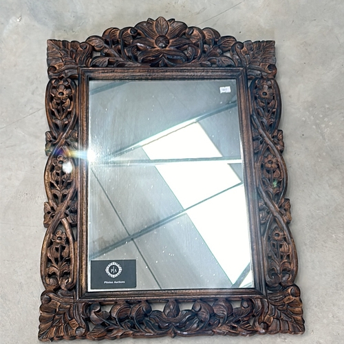 299 - Carved wooden mirror features intricate floral motifs and a rich patina.