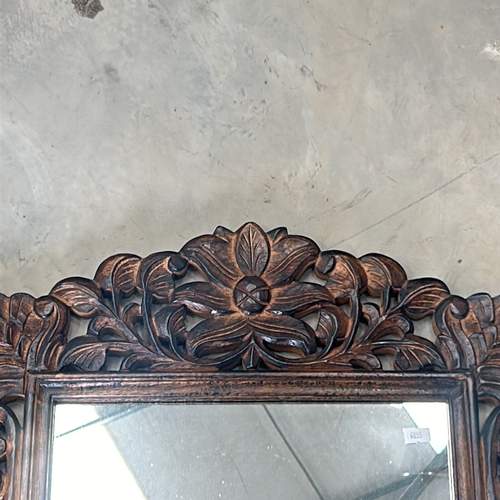 299 - Carved wooden mirror features intricate floral motifs and a rich patina.