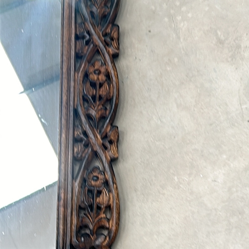 299 - Carved wooden mirror features intricate floral motifs and a rich patina.