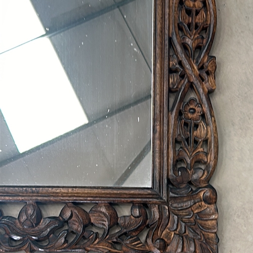 299 - Carved wooden mirror features intricate floral motifs and a rich patina.