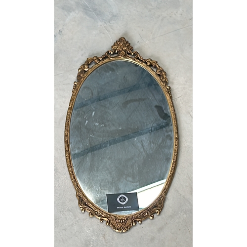 300 - Oval mirror with intricate floral gilded frame, from the vintage era. The frame features decorative ... 