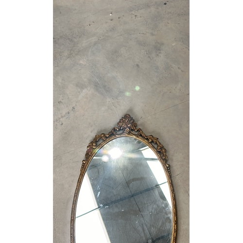 300 - Oval mirror with intricate floral gilded frame, from the vintage era. The frame features decorative ... 