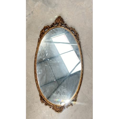 300 - Oval mirror with intricate floral gilded frame, from the vintage era. The frame features decorative ... 