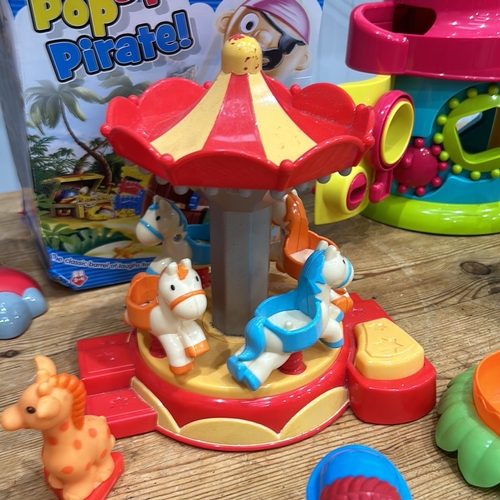 407 - Assorted plastic playset including carousel, dinosaur, train, and houses. Includes Pop-Up Pirate gam... 