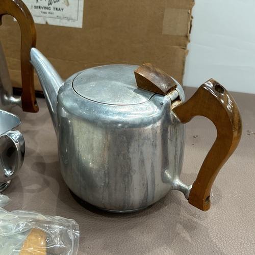 399 - Regent Piquot Ware aluminium tea set, featuring a teapot with wooden handle, creamer, and sugar bowl... 