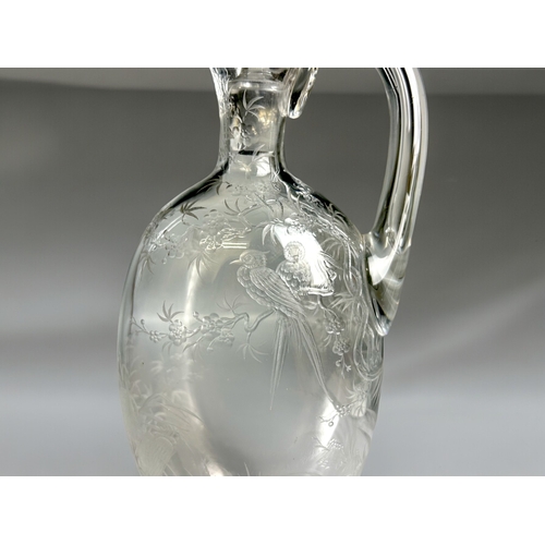 393 - A 19th century engraved glass claret jug.Finely engraved with tropical birds perched in blossoming t... 