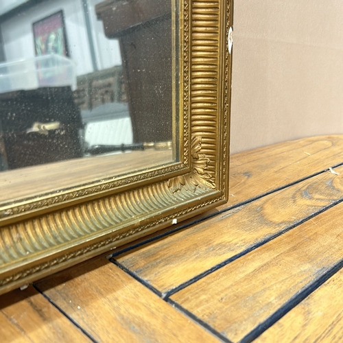 163 - Rectangular gilt mirror with ornate frame, featuring beaded and fluted detailing.