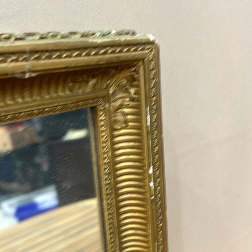 163 - Rectangular gilt mirror with ornate frame, featuring beaded and fluted detailing.