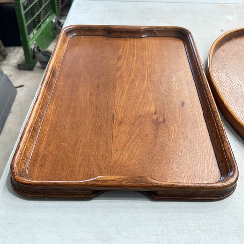 339 - Two Antique oak serving trays, rectangular and oval, featuring brass handles and smooth edges.