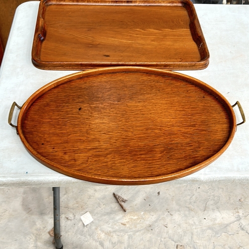 339 - Two Antique oak serving trays, rectangular and oval, featuring brass handles and smooth edges.