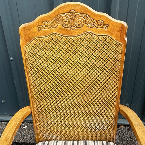 102 - Carved oak armchair with caned back and striped upholstered seat, featuring turned legs. Style is re... 