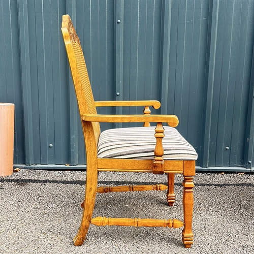 102 - Carved oak armchair with caned back and striped upholstered seat, featuring turned legs. Style is re... 