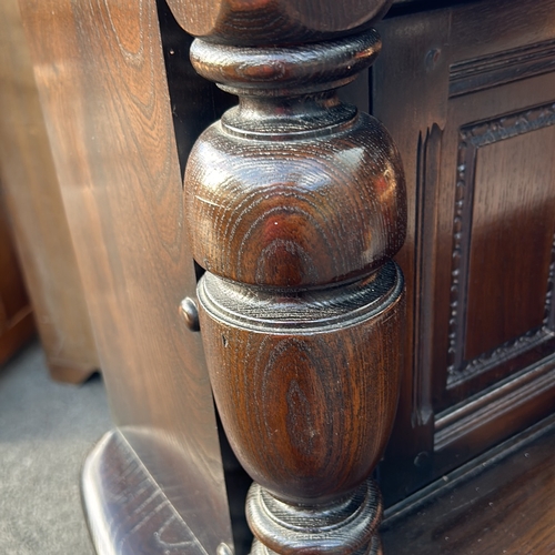 61 - Ercol dark wood sideboard features carved columns and paneled doors, offering ample storage. Ercol