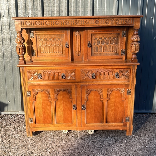 63 - Antique oak cabinet featuring intricate carved details and turned supports, from the Arts and Crafts... 