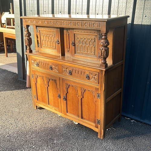 63 - Antique oak cabinet featuring intricate carved details and turned supports, from the Arts and Crafts... 