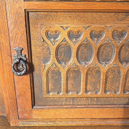 63 - Antique oak cabinet featuring intricate carved details and turned supports, from the Arts and Crafts... 