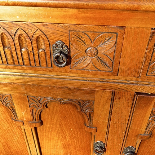 63 - Antique oak cabinet featuring intricate carved details and turned supports, from the Arts and Crafts... 