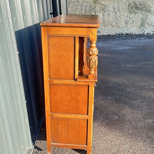 63 - Antique oak cabinet featuring intricate carved details and turned supports, from the Arts and Crafts... 