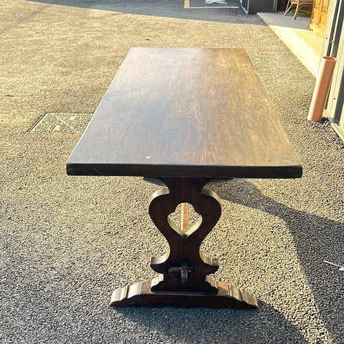 65 - Solid oak trestle table featuring a rectangular top and decorative carved base.