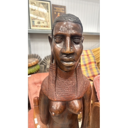 245 - Hand-carved wooden sculpture depicts a traditional African figure with intricate detail, standing on... 